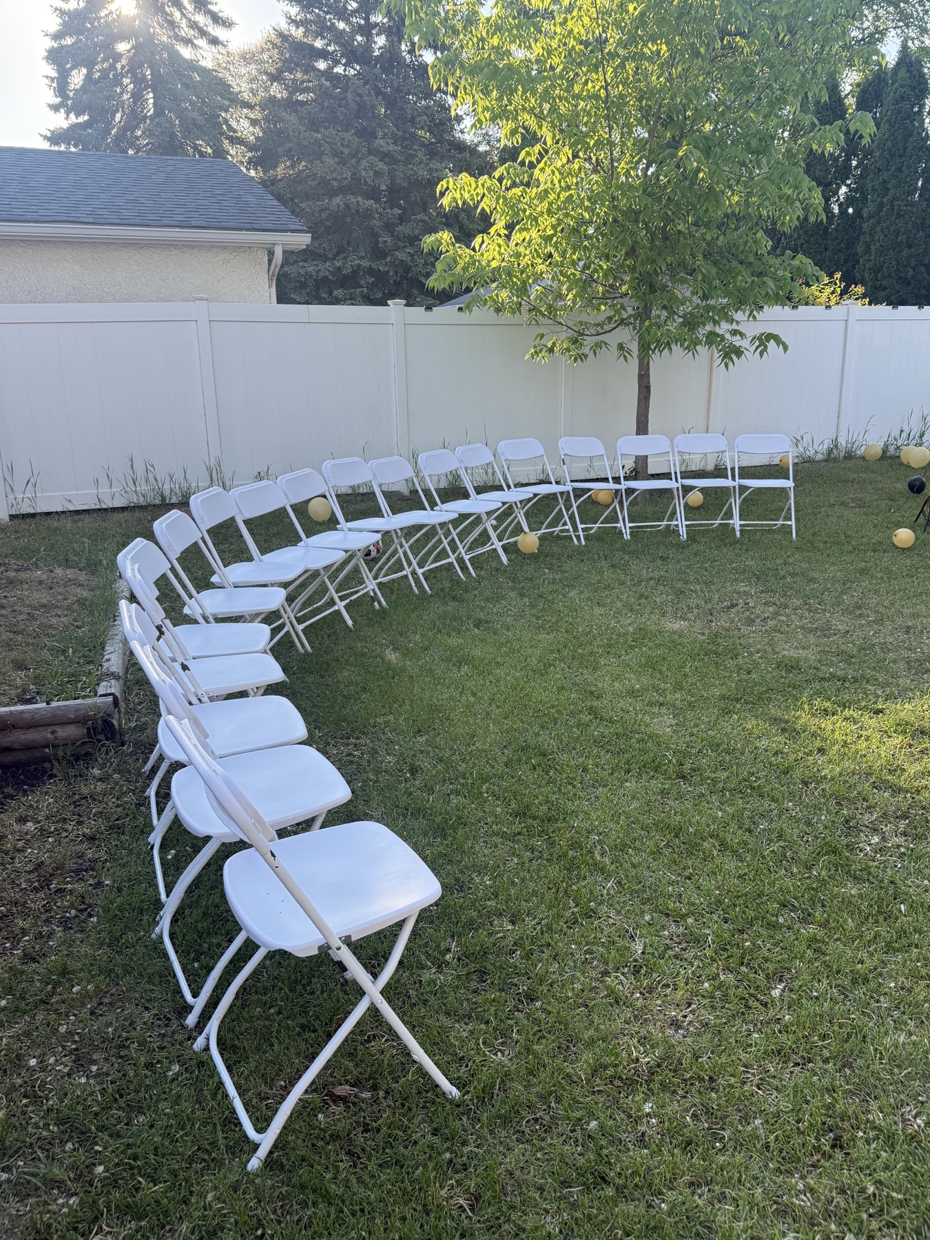 Rows of white folding chairs set up in a Winnipeg backyard
